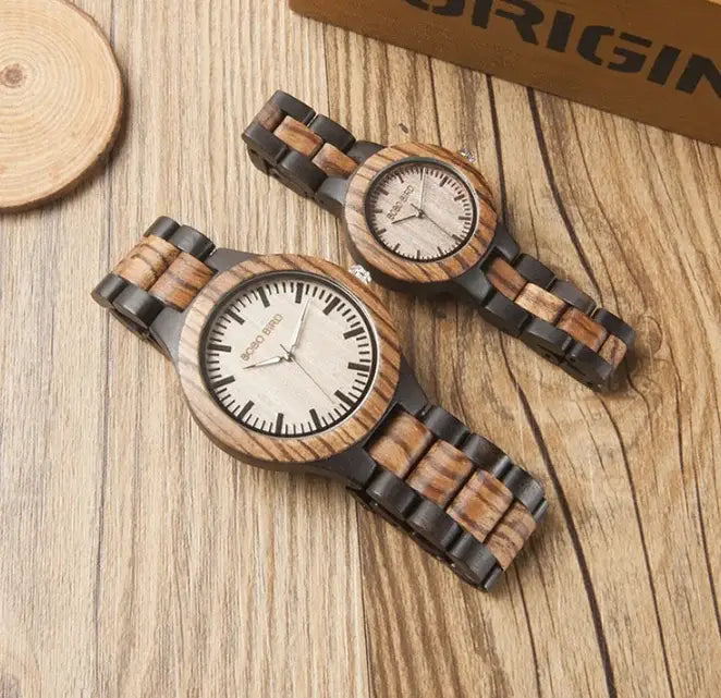 Wooden couple watches set with light wood dials and dark wood link bands on wooden surface