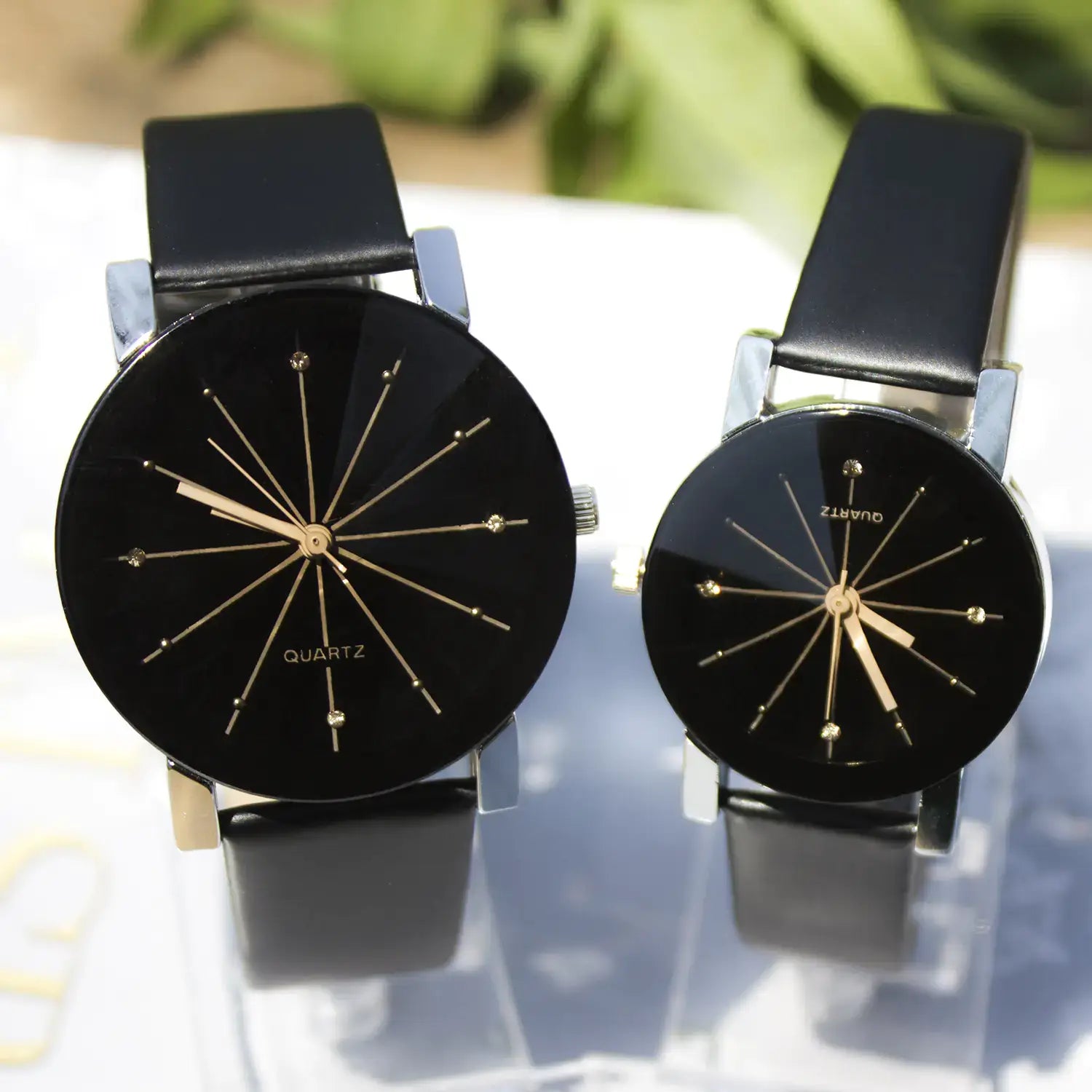 His and hers meridian watches with black leather straps and minimalist black dials with gold accents